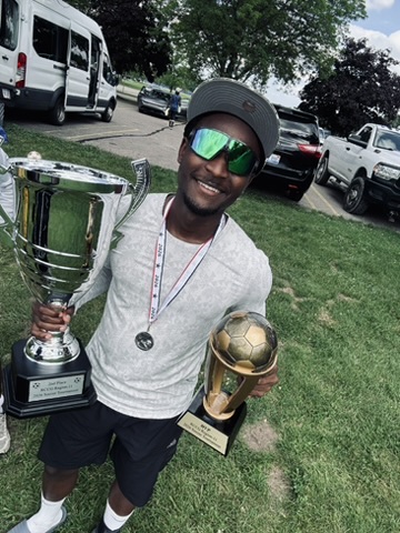 Mouhamad holding two football trophies